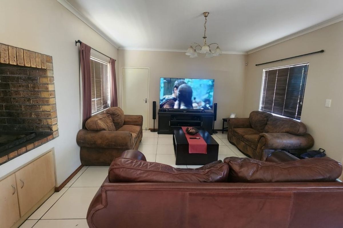 Spacious living room featuring a built-in brick fireplace, tiled flooring, and large windows with blinds, providing a comfortable and functional family space.