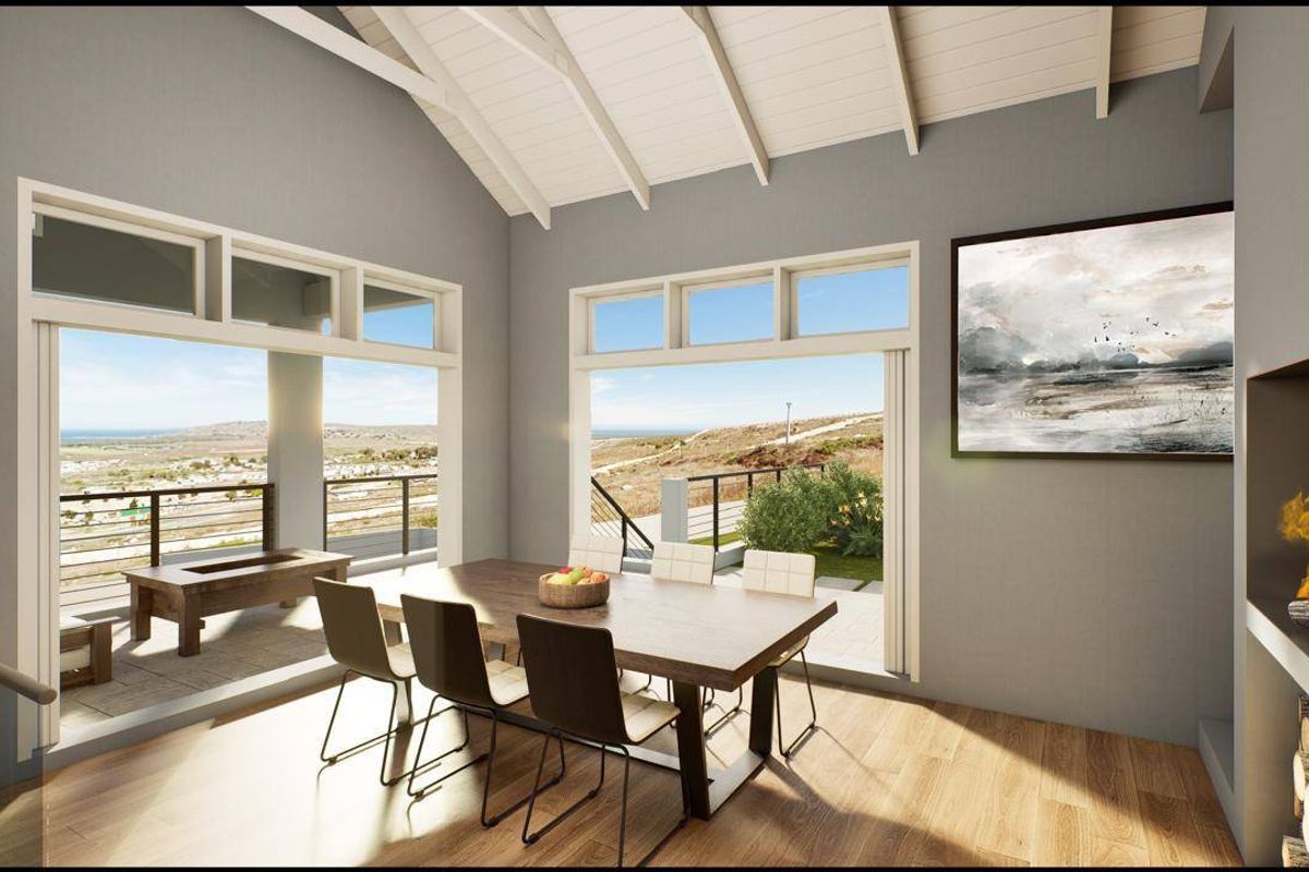 A bright dining area featuring a vaulted ceiling, built-in fireplace, and large sliding glass doors that open to a scenic outdoor view.