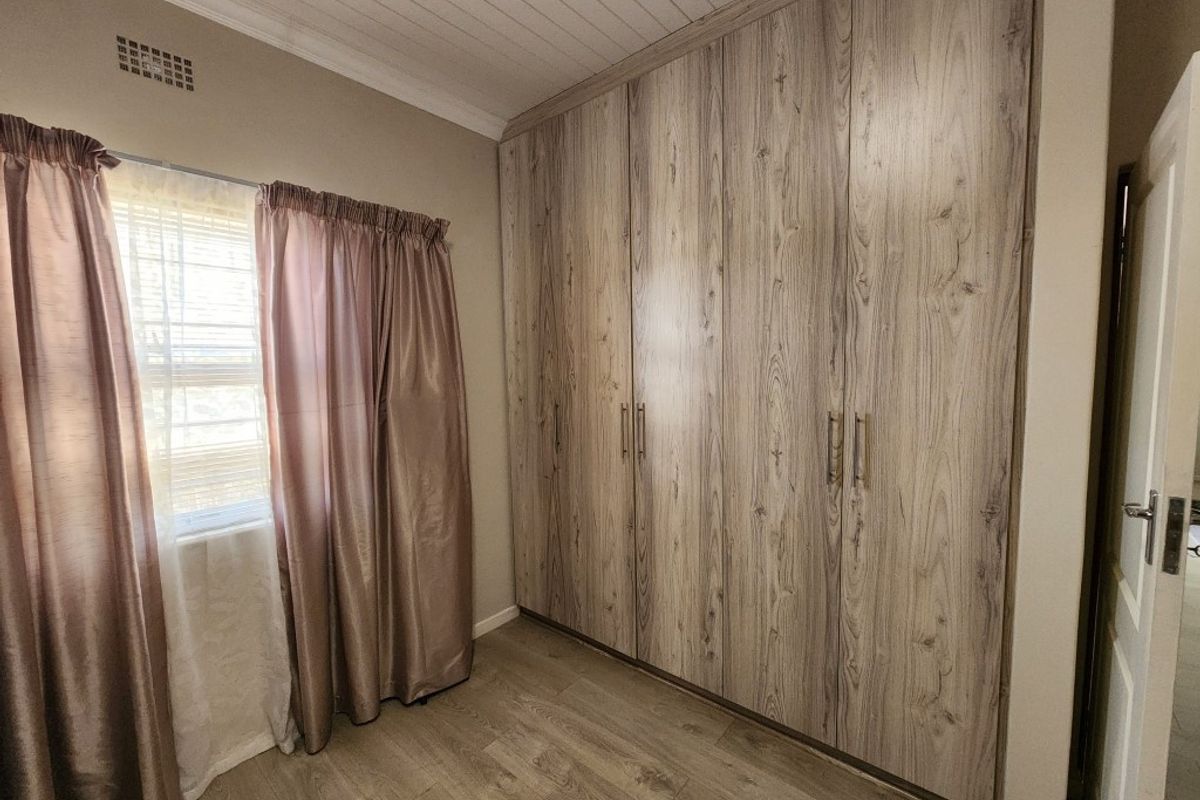 A bedroom featuring built-in wood-look cabinetry, laminate flooring, and a tongue-and-groove ceiling finish.