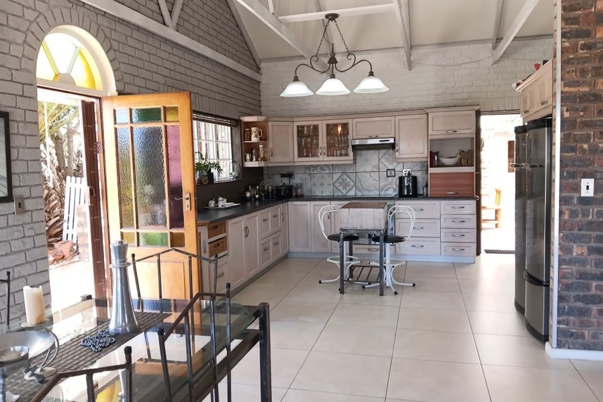 Spacious kitchen featuring exposed brick walls, vaulted ceilings, ample cabinetry, and tiled flooring, with direct access to the outdoor patio area.