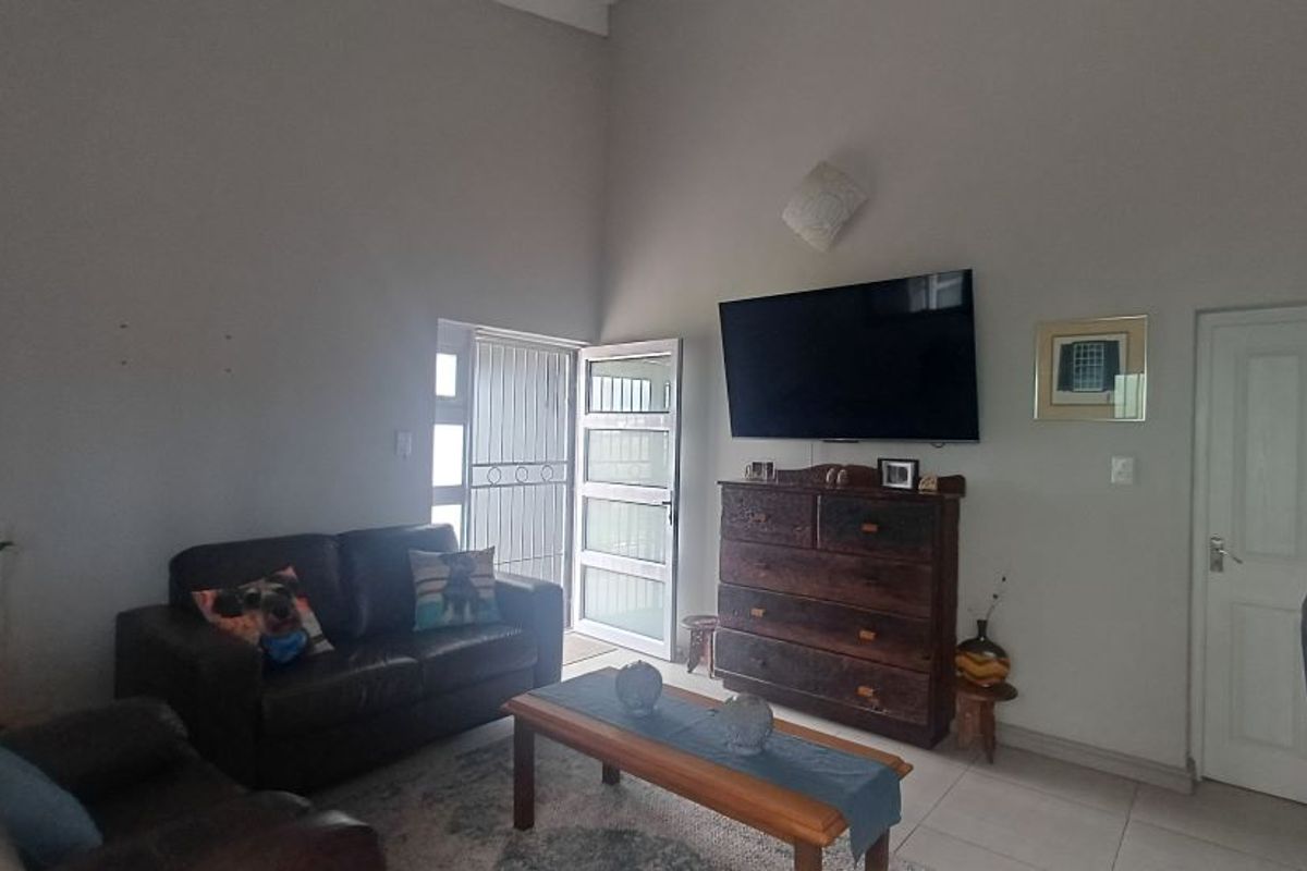 A living room featuring high ceilings, tiled flooring, and a direct access door with security gate.