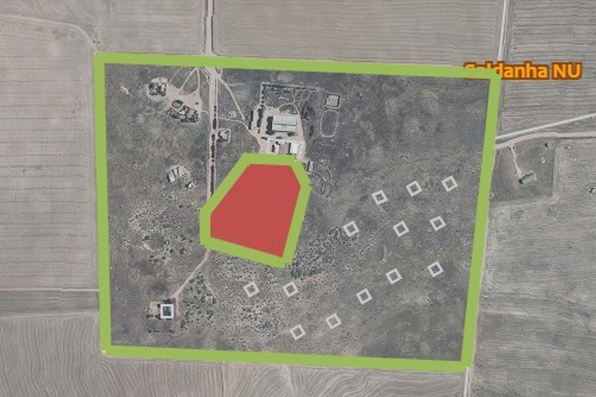 Aerial view of a large vacant residential land plot with marked boundaries and site layout indicators.