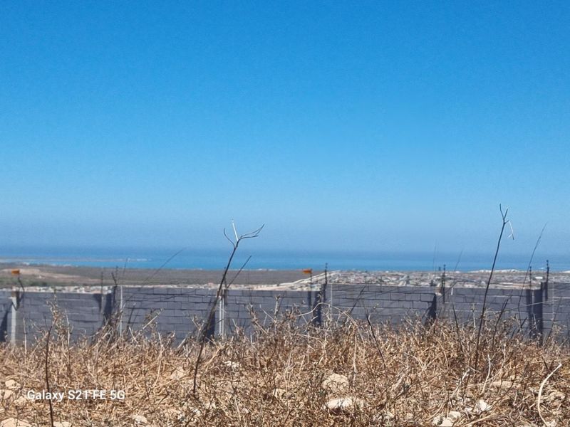 A view of the surrounding landscape and distant coastline from the vacant residential plot, featuring a perimeter wall with electric fencing.