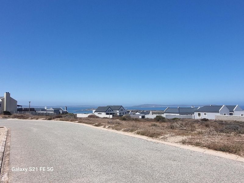 A street view of a residential area featuring paved roads and surrounding coastal landscape views.