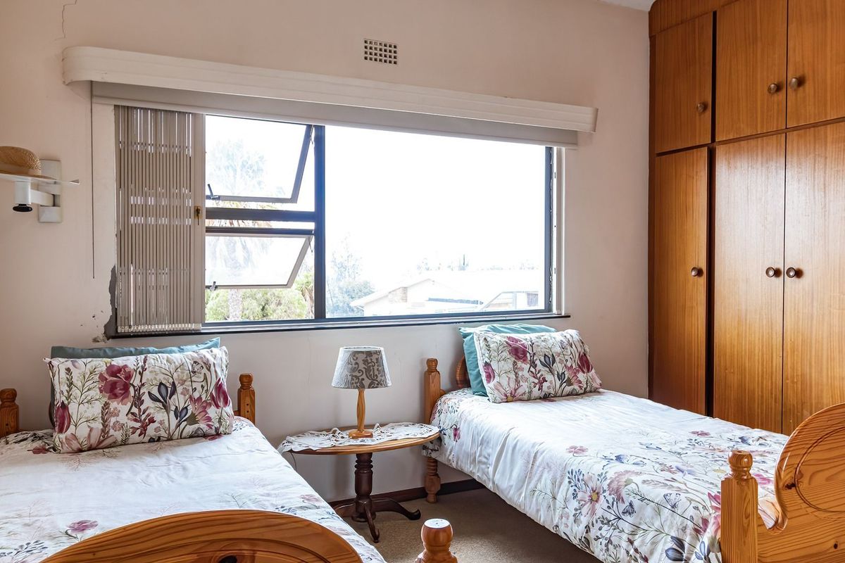 A bedroom featuring built-in wooden cupboards and a large window providing natural light.