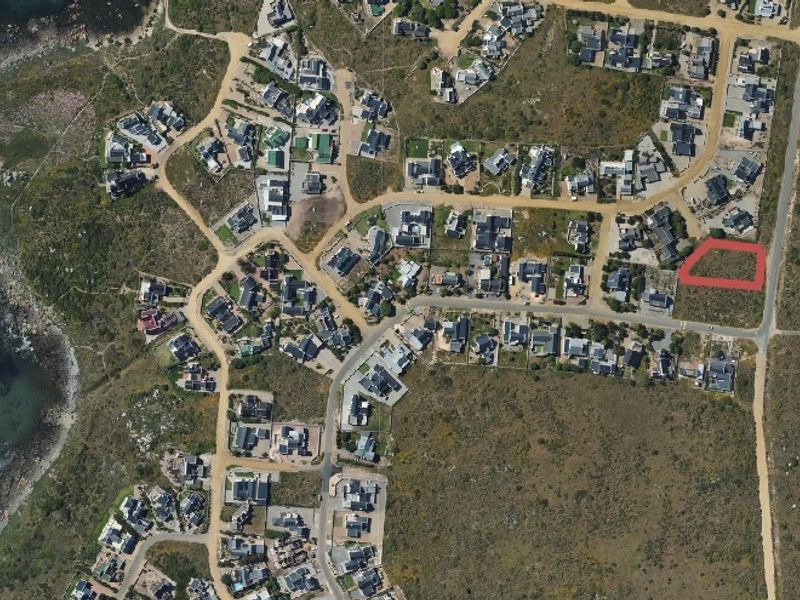 Aerial view of a residential coastal estate showing the vacant land plot highlighted in red, situated within a developed neighbourhood near the coastline.