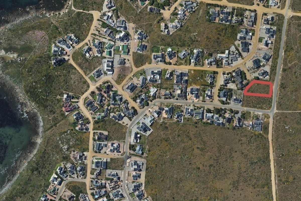 Aerial view of a residential coastal estate showing the vacant land plot highlighted in red, situated within a developed neighbourhood near the coastline.