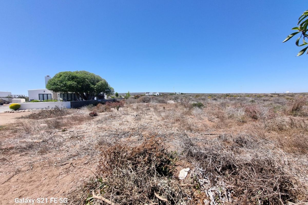 A wide-angle view of a vacant residential plot featuring natural coastal vegetation and surrounding landscape.