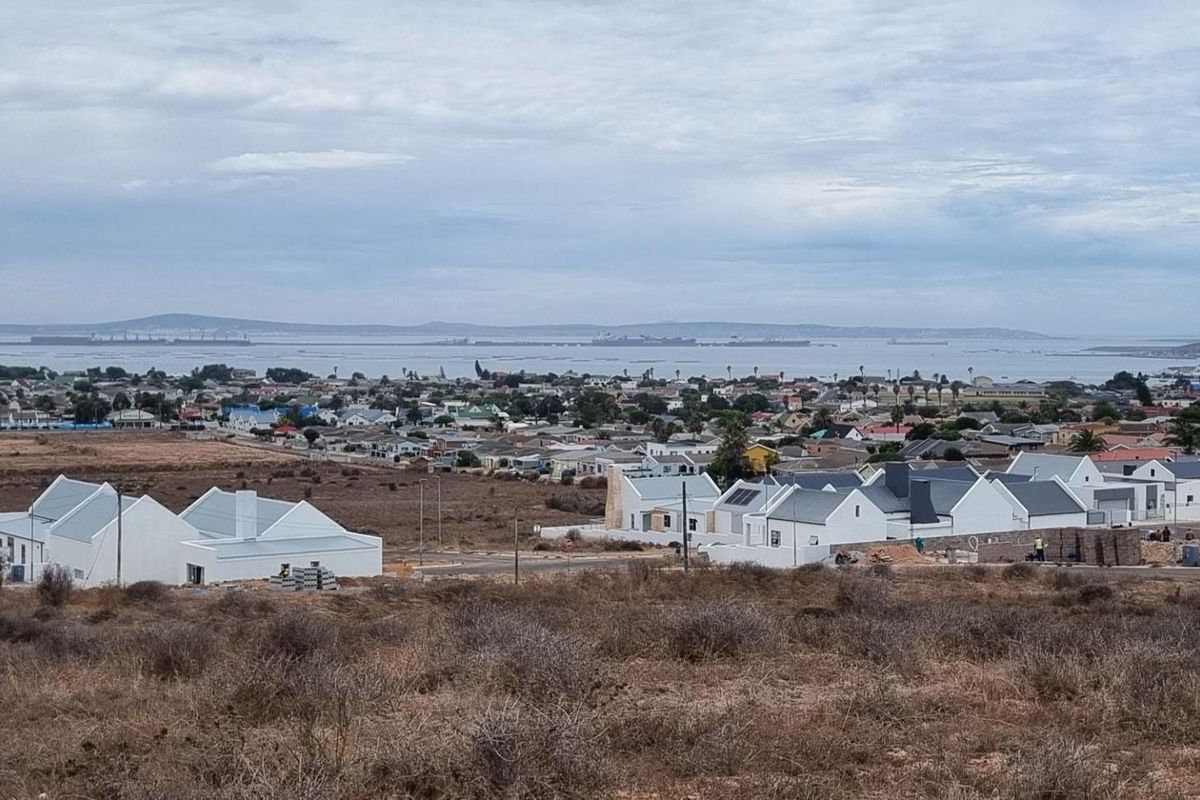 An elevated view overlooking a residential development with coastal scenery and distant water views in the background.