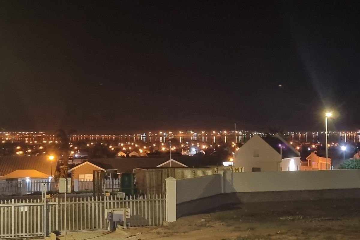 Night view overlooking a residential neighborhood with distant city lights and clear horizon.