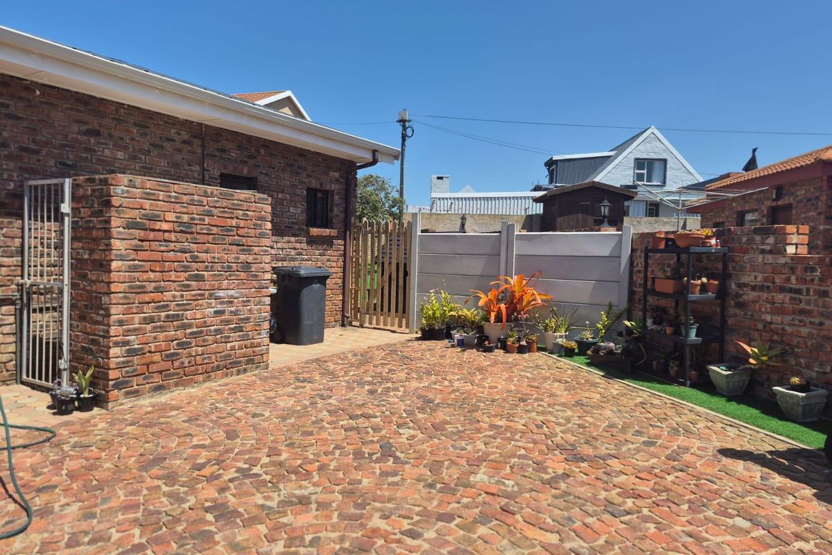 A private rear courtyard featuring durable brick paving, enclosed by a combination of face-brick walls and precast concrete fencing.