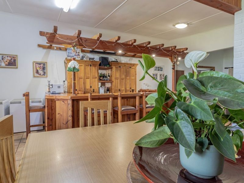A rustic indoor bar area featuring a built-in wooden counter, overhead timber pergola detailing, and tiled flooring, creating a cozy entertainment space.
