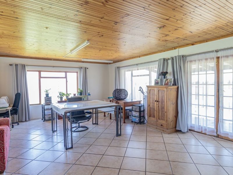 Spacious living area featuring a warm timber tongue and groove ceiling, ceramic tiled flooring, and large windows with access to the exterior.