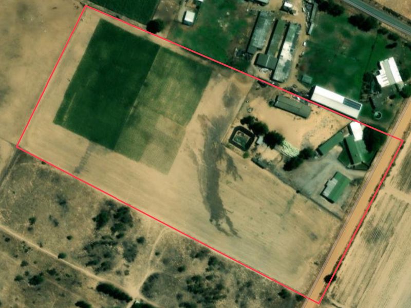 Aerial view of the farm property showing the layout of the main buildings, outbuildings, and surrounding cultivated agricultural land.