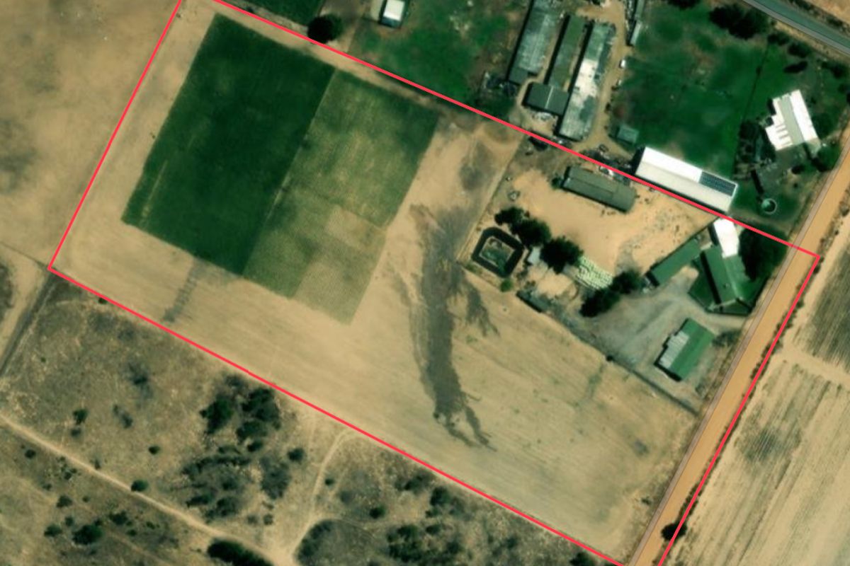 Aerial view of the farm property showing the layout of the main buildings, outbuildings, and surrounding cultivated agricultural land.