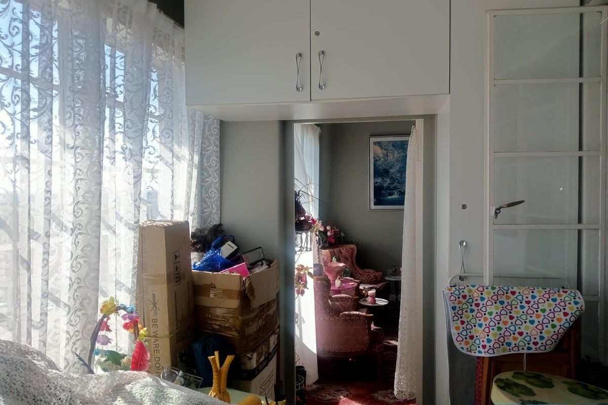 A bedroom interior featuring built-in overhead cabinetry and a built-in wardrobe, with a doorway leading to an adjacent room.