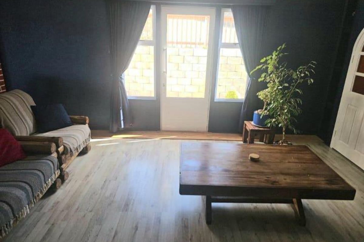 A living room featuring dark-painted walls, light-toned wood-look flooring, and a glass-paneled door providing access to the exterior.
