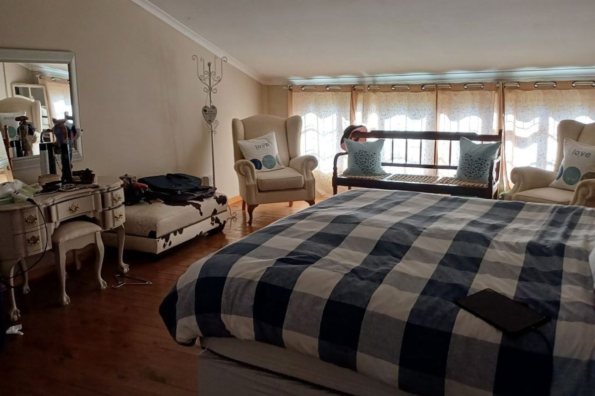 Spacious bedroom featuring vaulted ceilings, timber flooring, and large windows allowing for ample natural light.