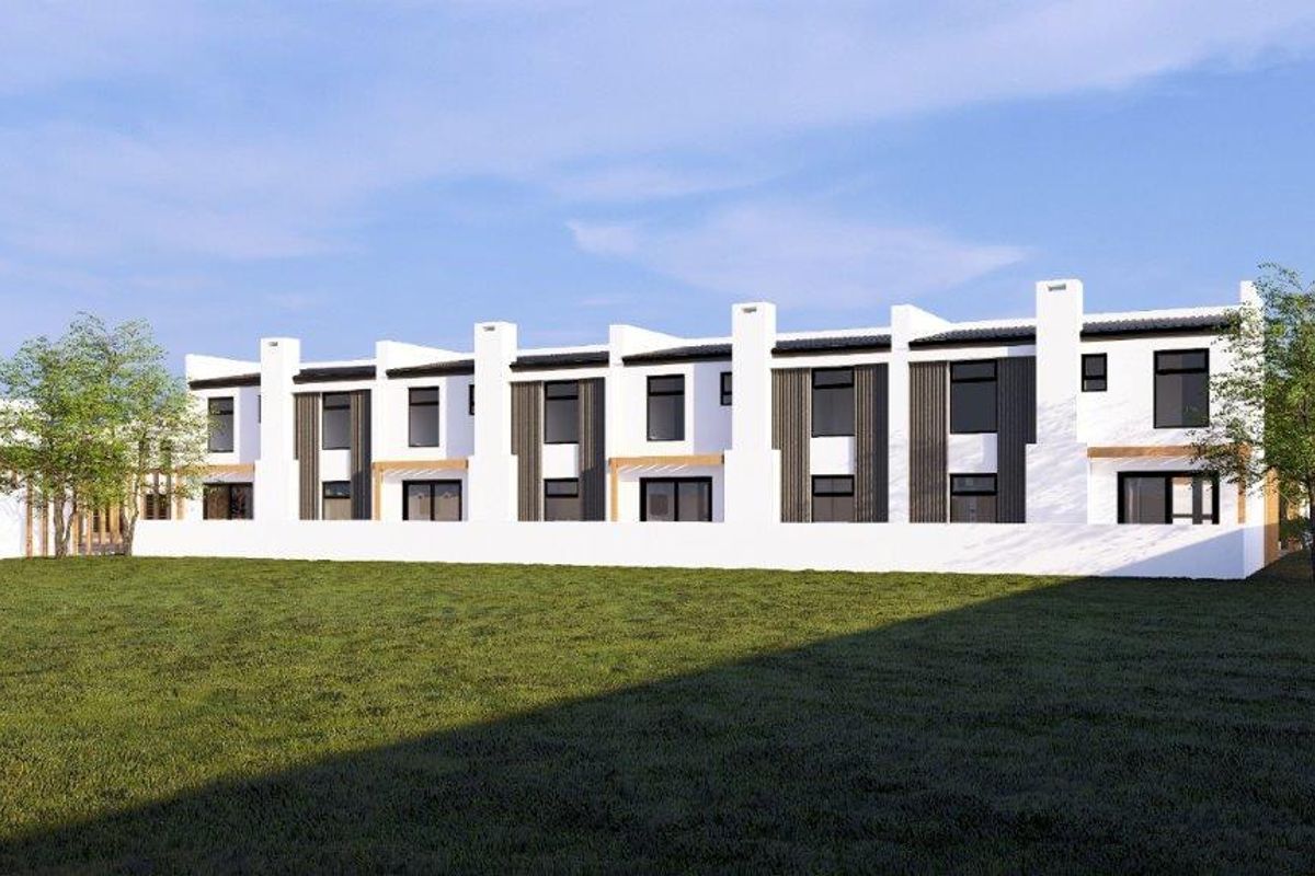 A modern residential townhouse complex featuring a clean white facade, dark vertical accents, and large windows overlooking a spacious green lawn.
