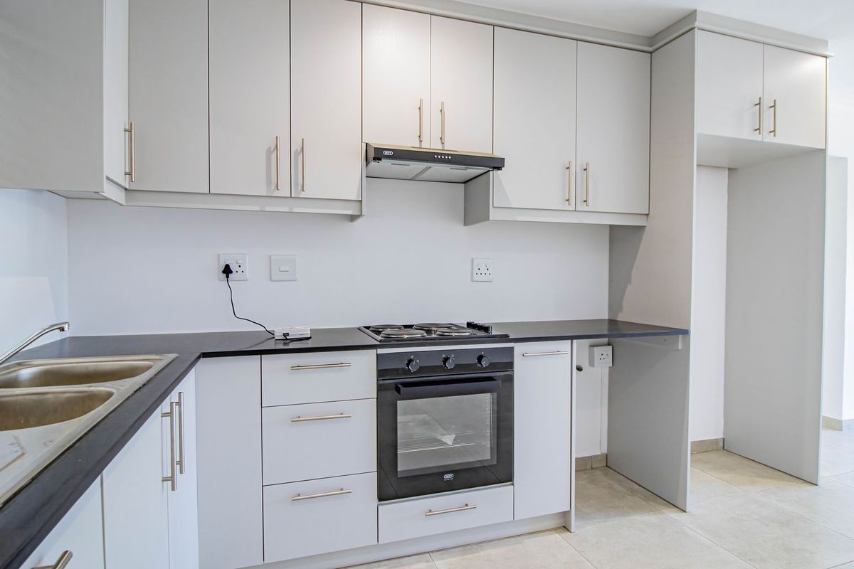 Modern kitchen featuring light-toned cabinetry, dark countertops, a built-in oven, gas hob, extractor fan, and a double-basin stainless steel sink.