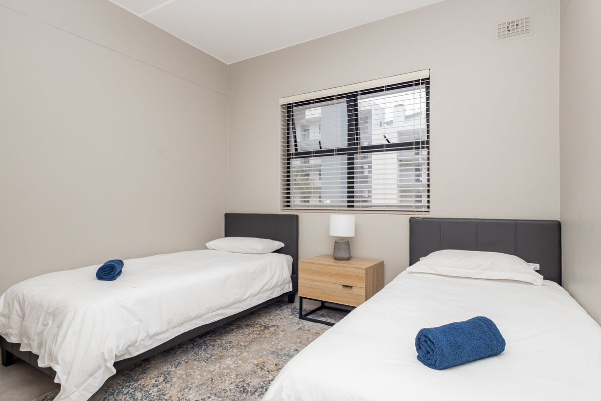 A well-maintained bedroom featuring neutral wall tones, a large window with fitted blinds, and integrated ceiling ventilation.