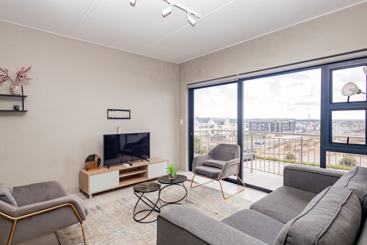 A bright living room featuring large sliding glass doors that open onto a balcony, providing natural light and views of the surrounding area.