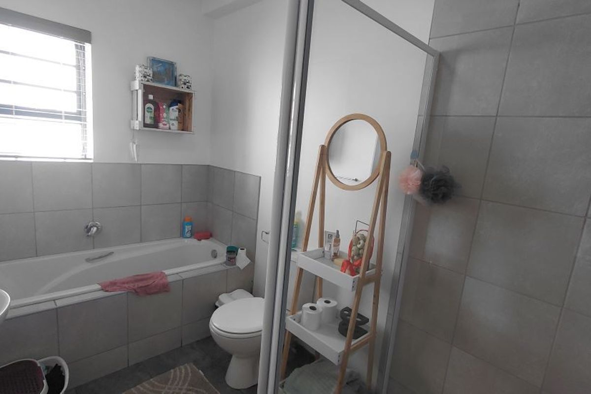 A functional bathroom featuring a built-in bathtub, a separate shower enclosure with tiled walls, and a standard toilet.