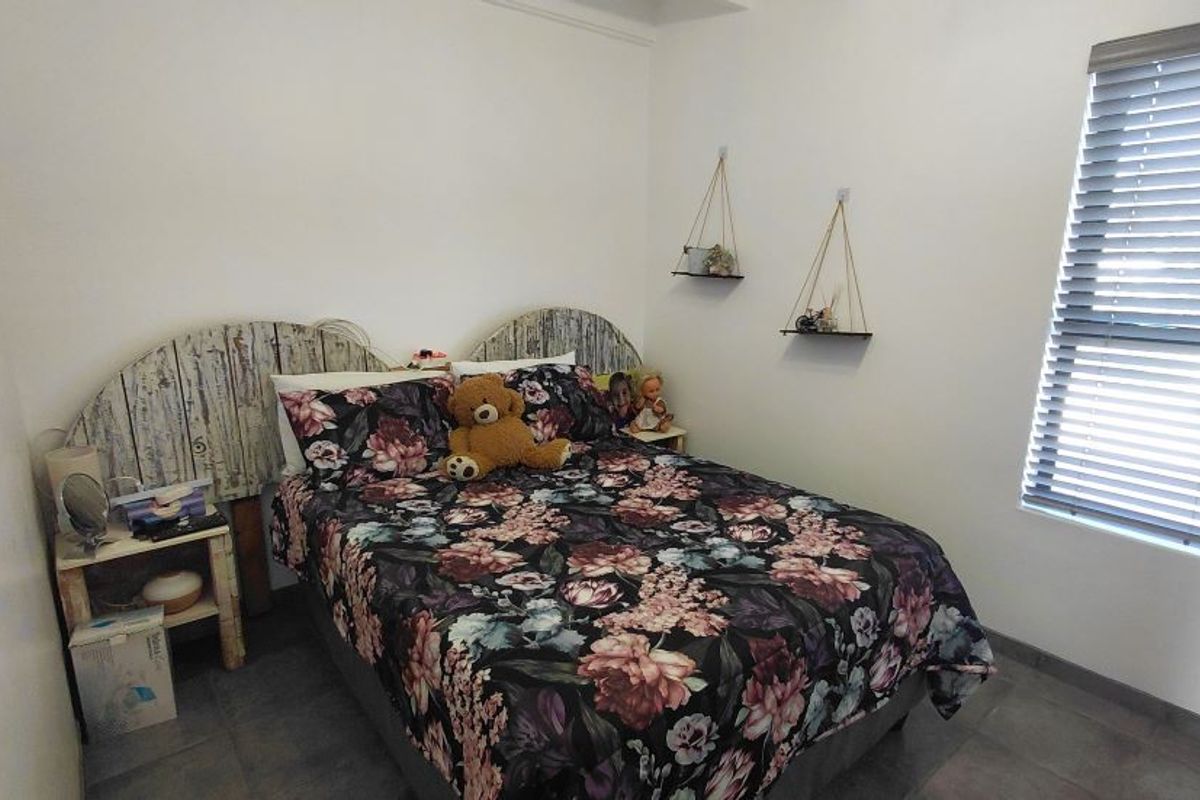 A bedroom featuring tiled flooring and horizontal window blinds, providing a neutral base for personalization.