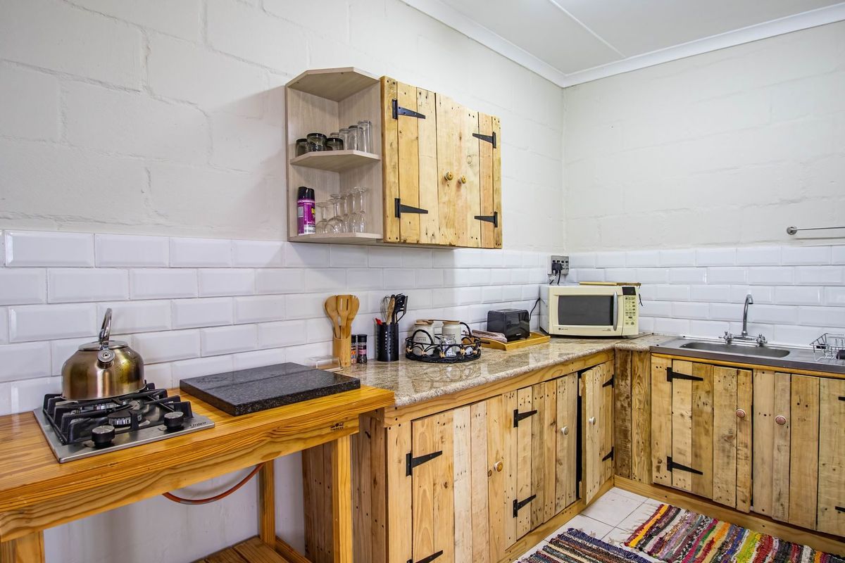 A rustic-style kitchen featuring custom wooden cabinetry, a built-in gas hob, granite-look countertops, and white subway tile backsplash.