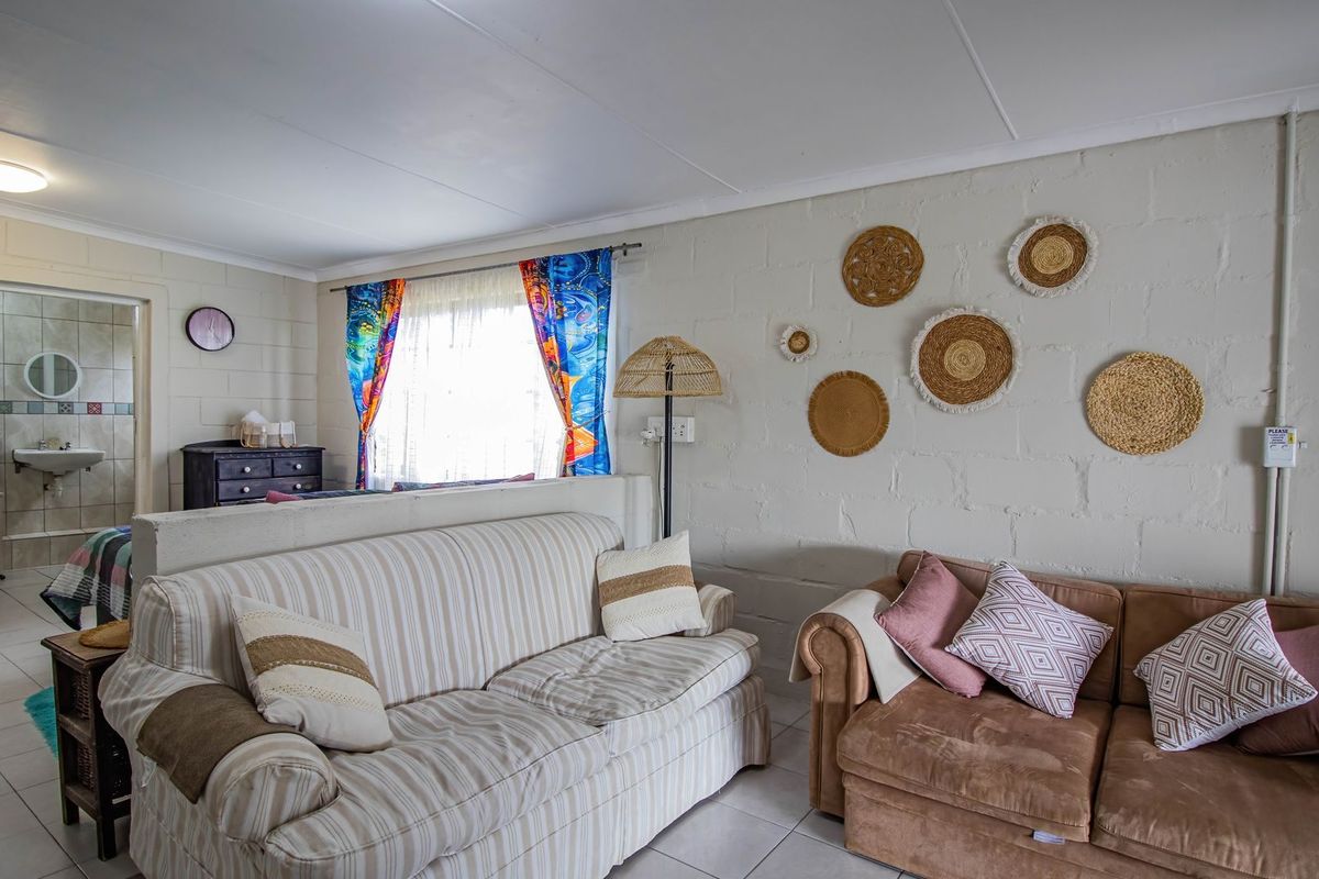 A living area featuring painted blockwork walls and tiled flooring, with an open-plan layout leading to an adjacent bathroom space.