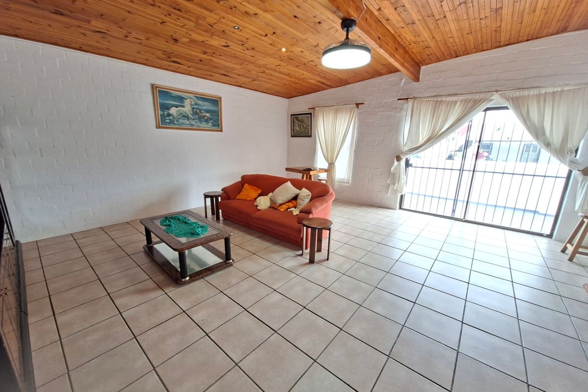 Spacious living area featuring a high timber-clad vaulted ceiling, tiled flooring, and large sliding glass doors providing access to the exterior.