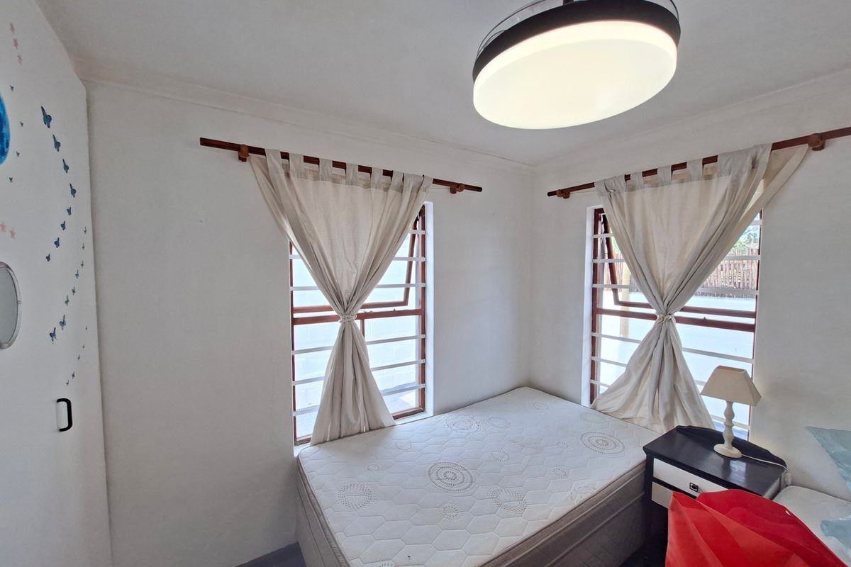 A bedroom featuring dual windows with security bars, a modern ceiling light fixture, and built-in cupboard space.