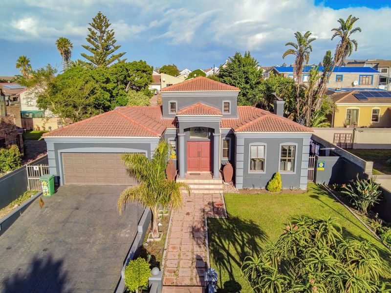 Aerial view of a detached house featuring a tiled roof, double garage, paved driveway, and a landscaped front garden with a paved walkway.
