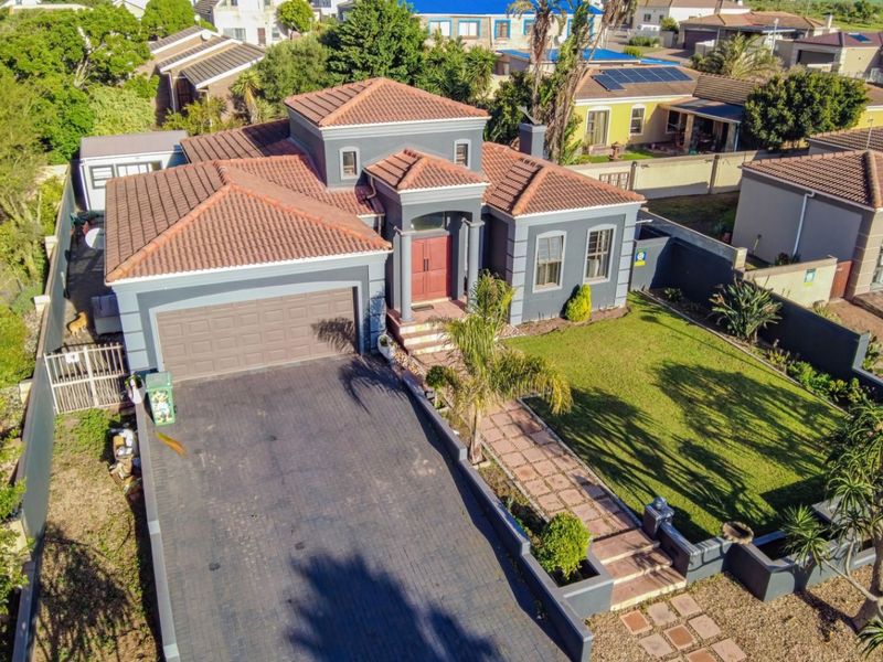Aerial view of a detached house featuring a tiled roof, paved driveway, double garage, and a well-maintained front garden with a paved walkway.