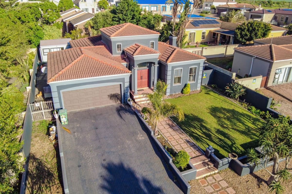 Aerial view of a detached house featuring a tiled roof, paved driveway, double garage, and a well-maintained front garden with a paved walkway.