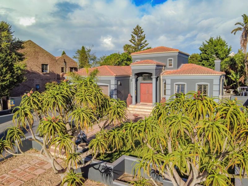 A well-maintained single-story residential property featuring a tiled roof, grey exterior facade, and a paved front entrance with established garden landscaping.