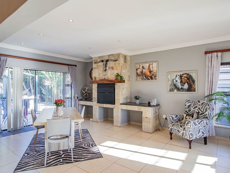 Open plan living and dining area featuring a stone-clad built-in fireplace, tiled flooring, and sliding glass doors leading to the outdoor patio.