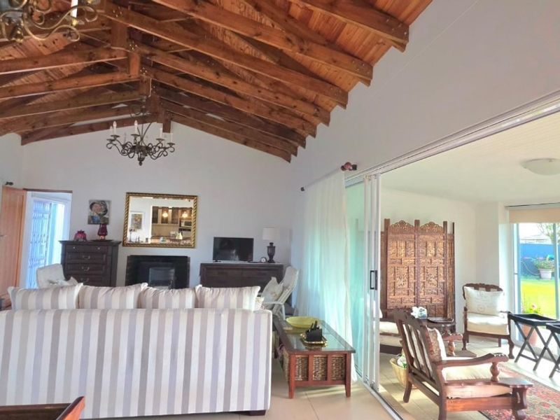 Spacious open-plan living area featuring an impressive exposed timber vaulted ceiling, a cozy fireplace, and large sliding glass doors opening to the garden.