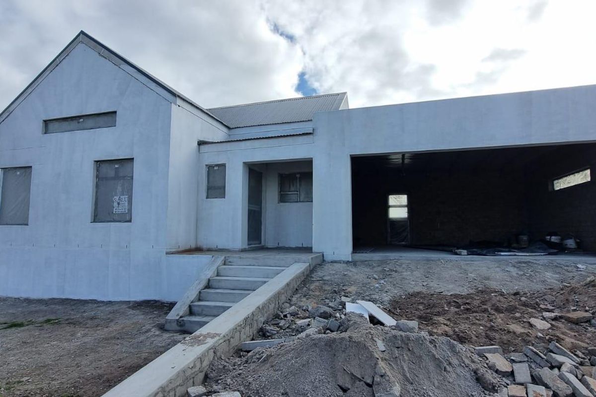 Front elevation of a house under construction, featuring a plastered facade, concrete entrance steps, and an integrated double garage.