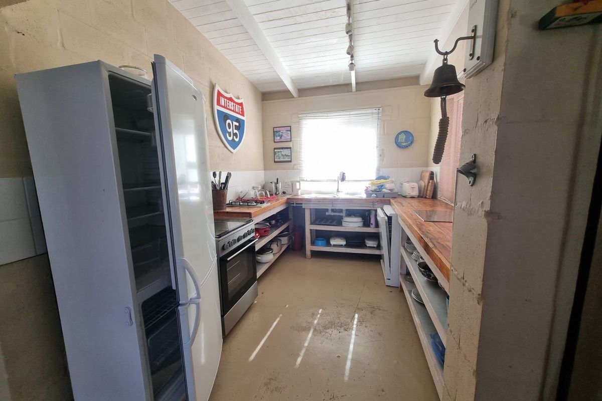 A rustic kitchen featuring timber benchtops, a freestanding oven, and exposed beam ceilings with concrete flooring.