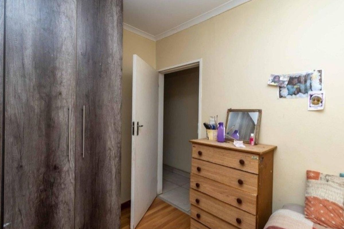 A bedroom featuring built-in wooden cabinetry and laminate flooring, providing functional storage space.