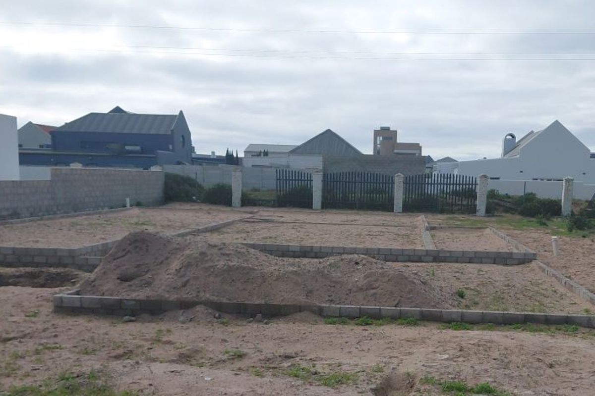 A vacant residential plot featuring an exposed concrete block foundation, ready for further construction and development.