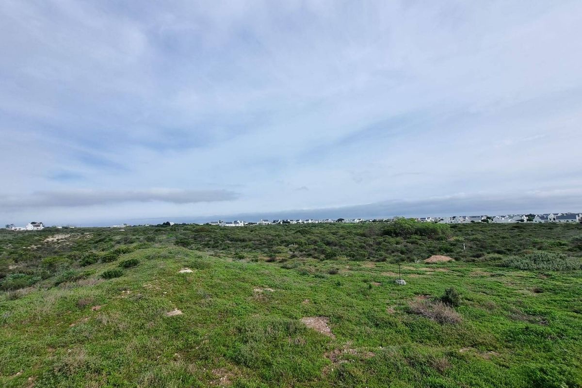 A wide-angle view of the vacant residential land featuring natural coastal vegetation and surrounding neighborhood landscape.