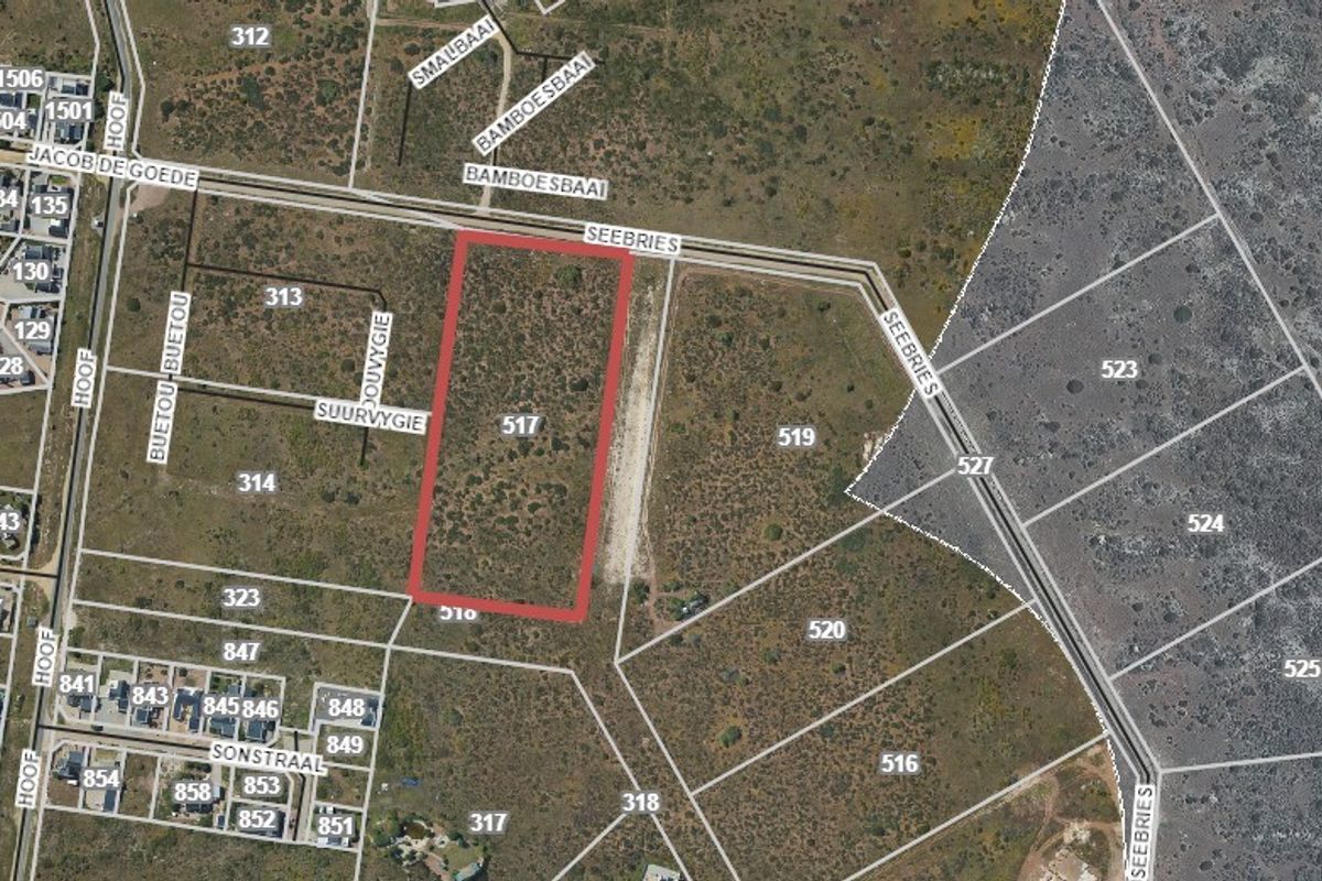 An aerial view of a vacant residential plot highlighted in red, situated within a developing coastal neighborhood.