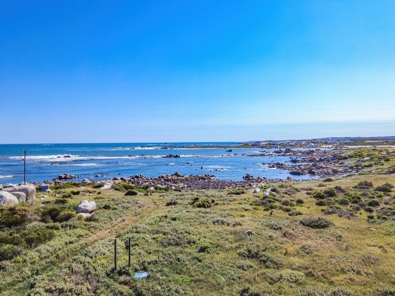 A scenic aerial view of the coastal landscape, featuring natural vegetation, rocky terrain, and an expansive ocean outlook.