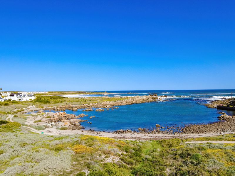A scenic aerial view of the coastal landscape, featuring a rocky shoreline and clear ocean waters, highlighting the natural beauty of the property location.