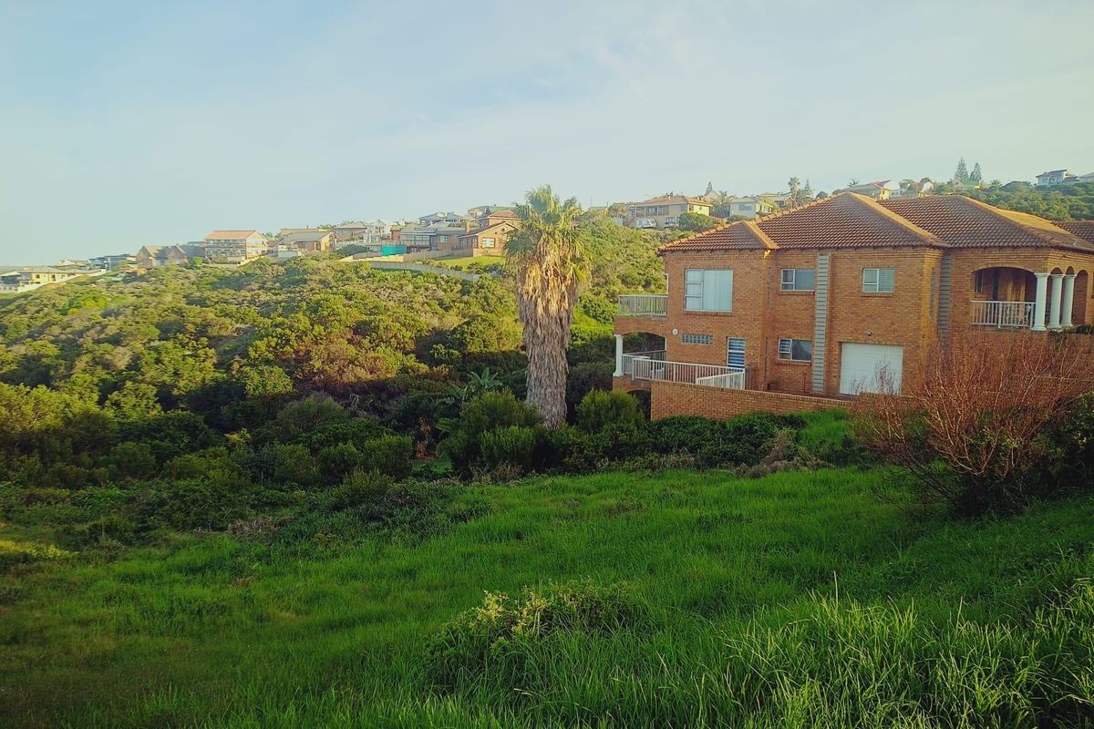 A view of a multi-story brick residential property set against a hillside landscape with surrounding greenery and neighborhood views.