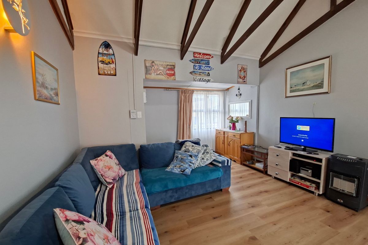 A cozy living room featuring vaulted ceilings with exposed timber beams and durable laminate wood flooring, creating a warm and inviting atmosphere.