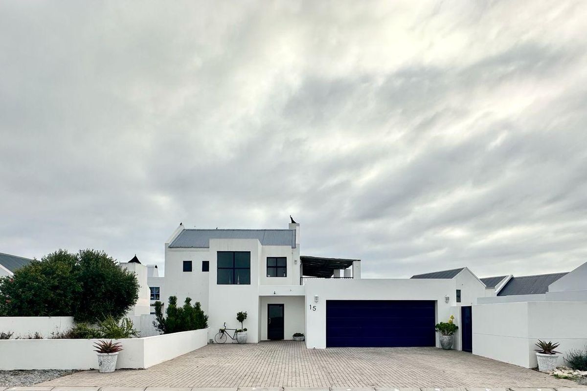 A modern two-story residential property featuring a white facade, a double garage, and a paved driveway under a cloudy sky.
