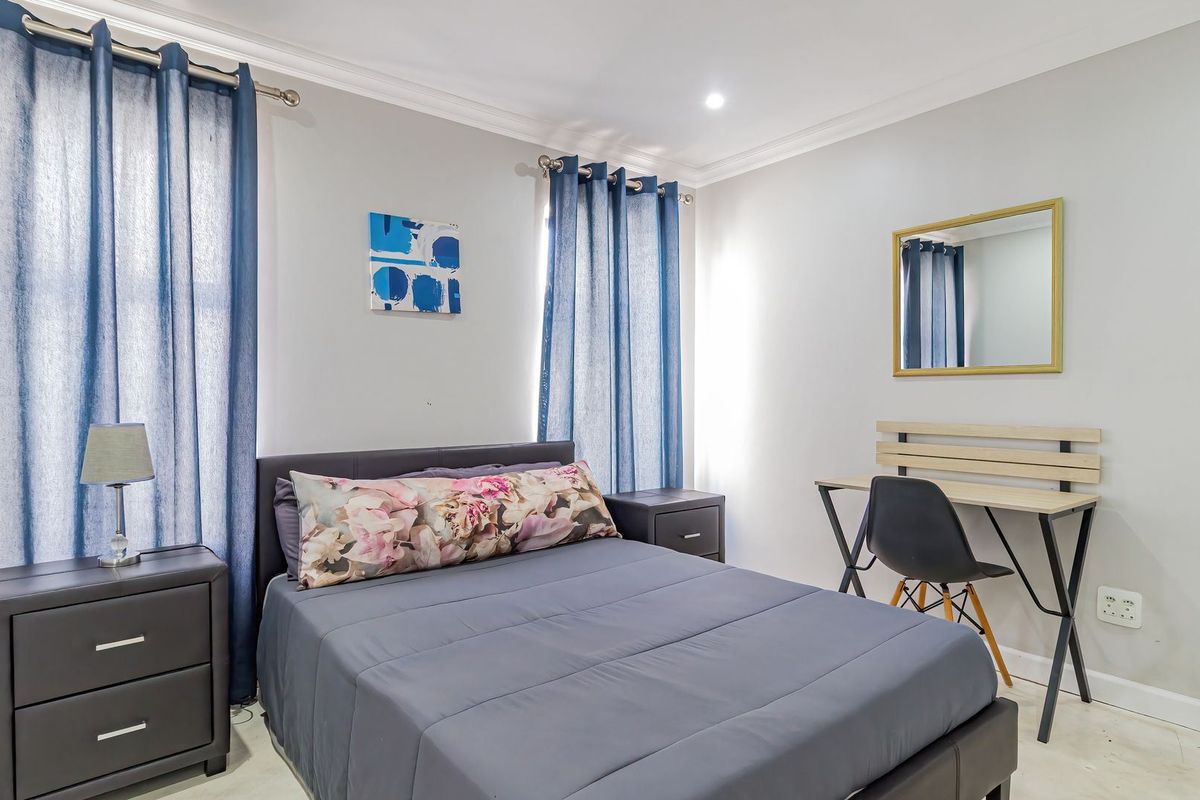 A well-maintained bedroom featuring neutral wall finishes, cove cornicing, and recessed downlighting, providing a clean and functional living space.